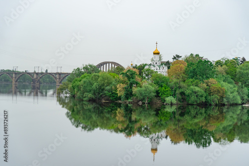 Church with golden domes and place religion of orthodox christian. Beautiful landscape with green park in middle of river. View of monastyrsky island with church of saint Nicholas in Dnipro Ukraine. photo