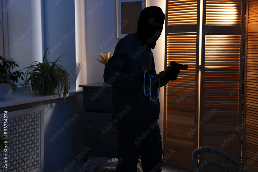 Thief with gun stealing jewels in foreign house. Burglary Thief with gun stealing jewels in foreign house. Burglary