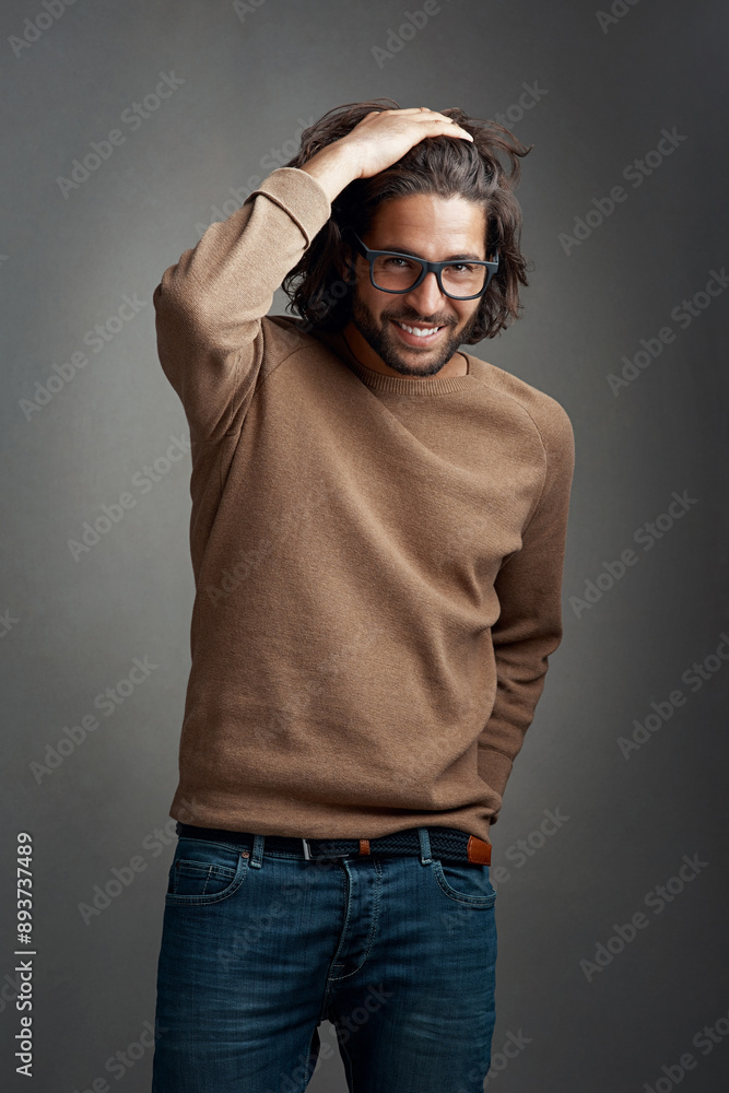 Naklejka premium Fashion, portrait and man in studio with smile for trendy clothes, casual outfit or denim jeans on gray background. Style, wardrobe and male model for designer glasses, winter jersey or confidence