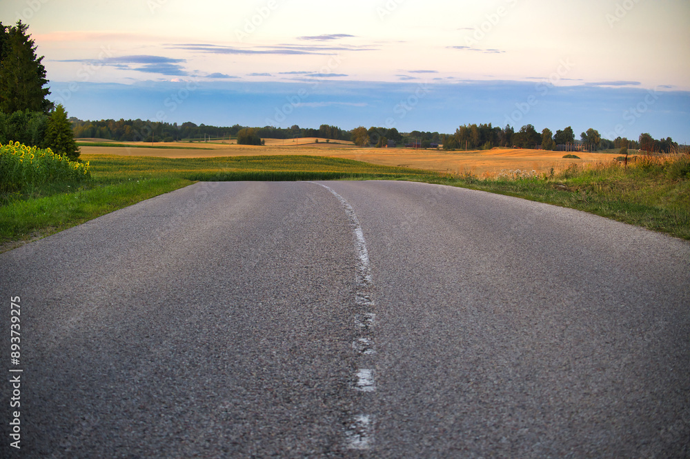 Empty rural road with scenic countryside at sunset Empty rural road with scenic countryside at sunset