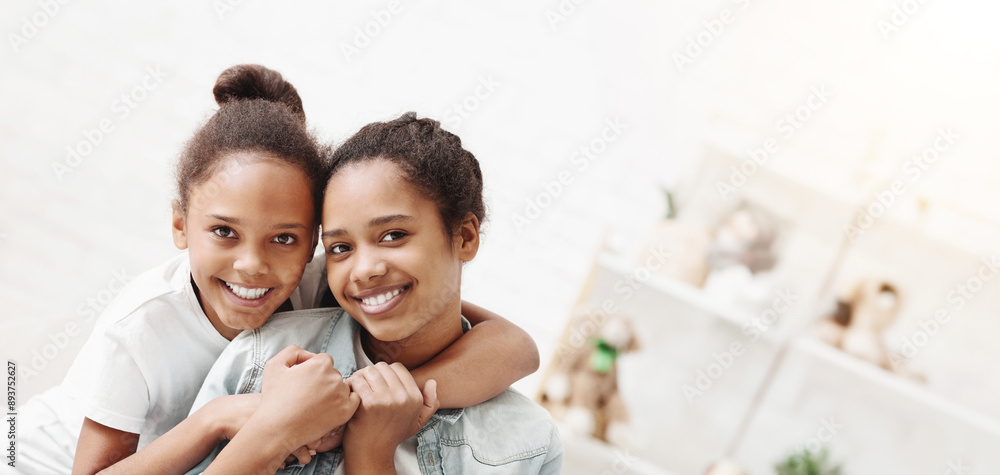 Two cute african american sisters hugging each other at home Two cute african american sisters hugging each other at home
