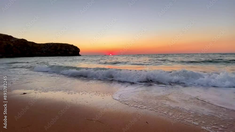 Close-up of foaming waves crashing onto a golden sandy shore against a beautiful sunset sky. High quality 4k footage Close-up of foaming waves crashing onto a golden sandy shore against a beautiful sunset sky. High quality 4k footage