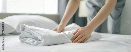 Wallpaper Mural Close-up of hands neatly folding white bed linens on a freshly made bed, emphasizing cleanliness and hospitality in a serene bedroom setting. Torontodigital.ca