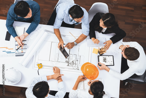 Top view banner of diverse group of civil engineer and client working together on architectural project, reviewing construction plan and building blueprint at meeting table. Prudent