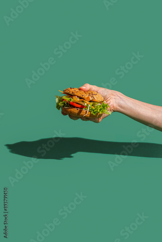 Close-up on a sandwich in a female hand on a green background