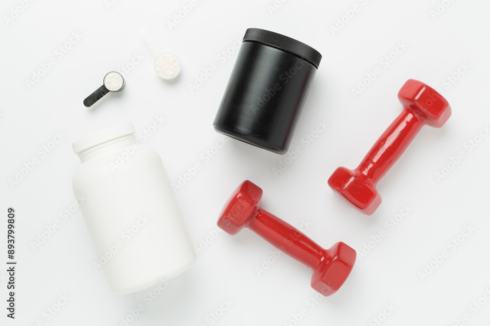 Fototapeta premium Jars with protein powder and dumbbells on color background, top view. Sports nutrition concept