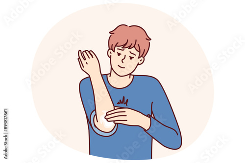 Man smears elbow with healing ointment after bruise or skin problems and acne. Young guy uses analgesic dermatological ointment to treat elbow joint and take care of skin in need of moisture