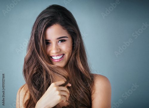 Hair care, portrait and woman in studio with shiny, collagen and volume treatment for beauty. Smile, confident and female person with brunette, long and salon hairstyle by gray background with mockup