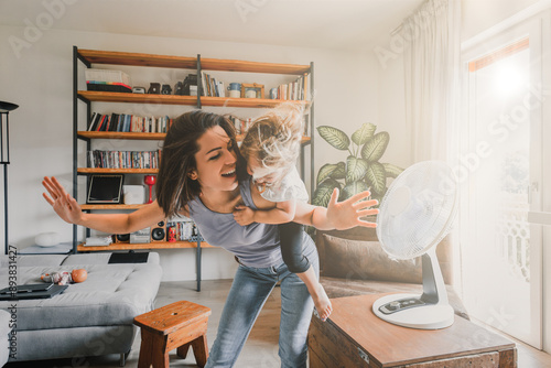 Happy family having fun cooling off with electric fan