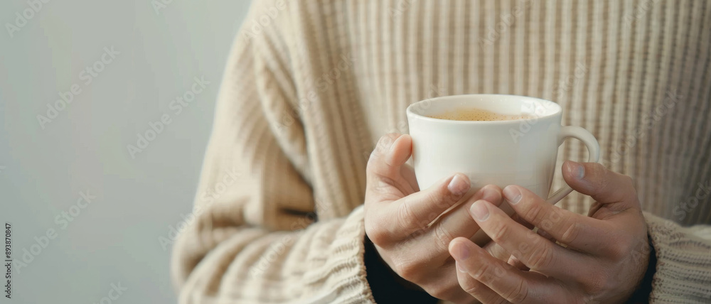 A person in a warm, cozy sweater holds a steaming cup of tea, reflecting serenity and comfort. A person in a warm, cozy sweater holds a steaming cup of tea, reflecting serenity and comfort.