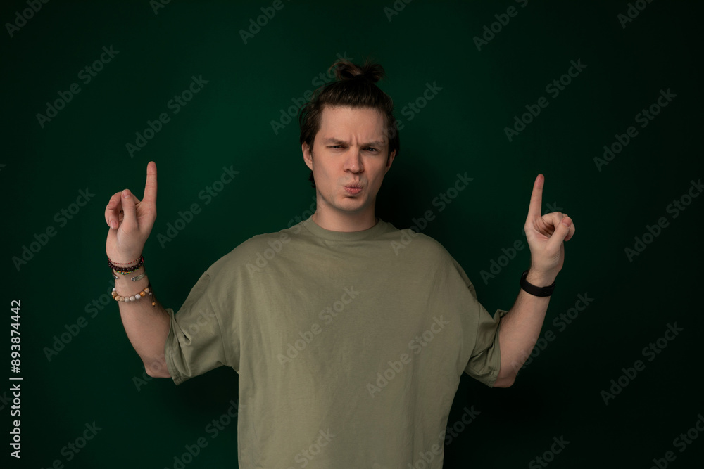 Man Standing in Front of Green Wall Holding Two Fingers Up Man Standing in Front of Green Wall Holding Two Fingers Up