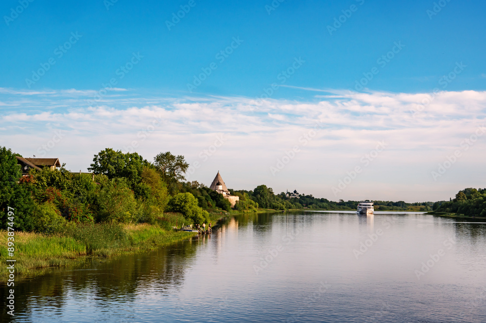 Beautiful morning landscape of the banks of the Volkhov River. In the distance is a cruise ship and a medieval fortress Beautiful morning landscape of the banks of the Volkhov River. In the distance is a cruise ship and a medieval fortress