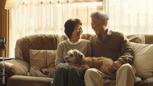 Happy elderly couple with a dog sitting on a cozy couch, gazing lovingly at each other in a sunlit room, symbolizing companionship and joy.