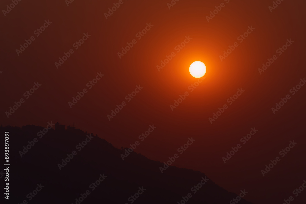 Tranquil view of the sun and mountain silhouette at sunset in Pokhara, Nepal Tranquil view of the sun and mountain silhouette at sunset in Pokhara, Nepal