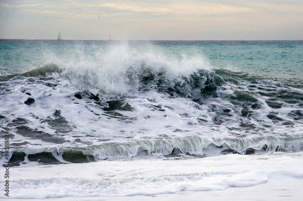 Fototapeta premium Waves of Bordighera sea at sunset. Bordighera is located 20 kilometres (12 mi) from the land border between Italy and France.