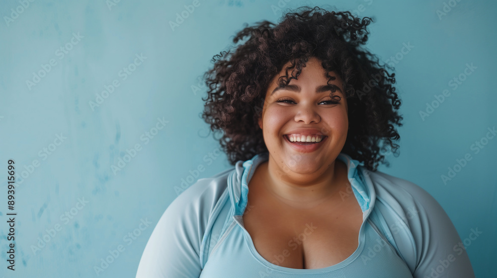 Confident plus-size woman in workout clothes, cheerful and relaxed, against a blue background. Confident plus-size woman in workout clothes, cheerful and relaxed, against a blue background.