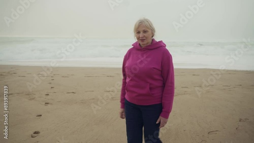 a senior caucasian woman walking along the sandy beach photo