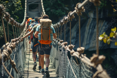 Group of active tourists with backpacks walking along rope bridge photo