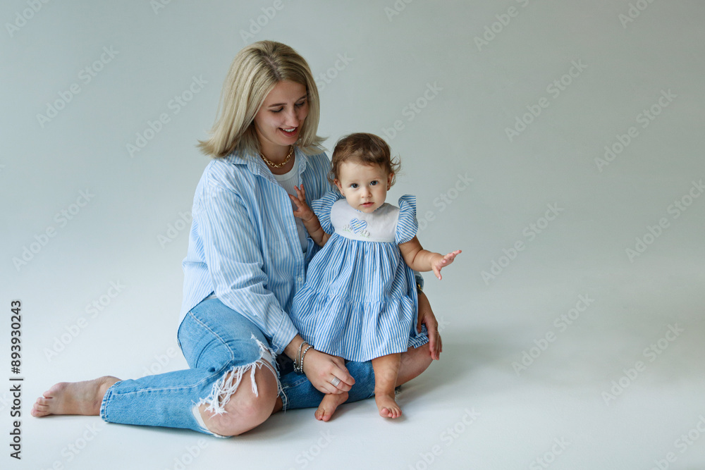 Front view of a beautiful young mother embracing her cute little 1 year old girl, isolated at studio over white background Front view of a beautiful young mother embracing her cute little 1 year old girl, isolated at studio over white background