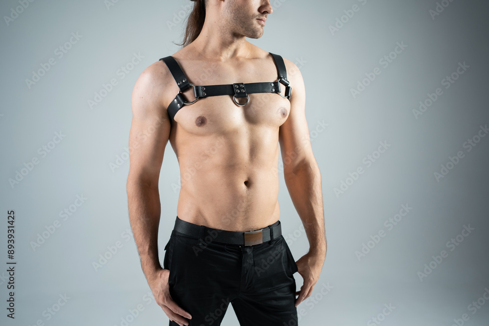 Fototapeta premium handsome naked stripper man in black leather bdsm harness, attractive sexy striptease male in fetish sexual clothes, queer and gay lgbt accessory