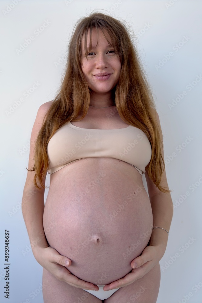 Happy pregnant young woman on white background in lingerie Happy pregnant young woman on white background in lingerie