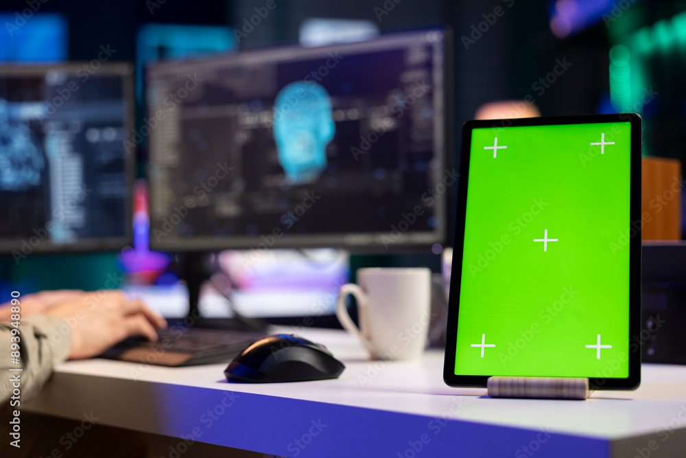 Focus on isolated screen tablet next to man in blurry background talking with AI gaining consciousness. Chroma key device on desk next to programmer, chatting with artificial intelligence, close up Focus on isolated screen tablet next to man in blurry background talking with AI gaining consciousness. Chroma key device on desk next to programmer, chatting with artificial intelligence, close up