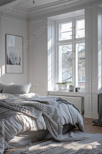 Luxury bedroom with white walls, wooden floor, comfortable king size bed with grey blanket and large windows.