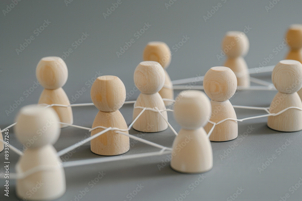 Obraz premium Wooden figures connected by lines, representing the concept of network and social interaction. People connecting in an office or business setting.