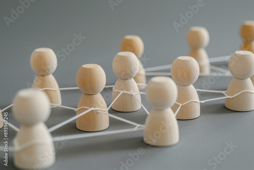 Wooden figures connected by lines, representing the concept of network and social interaction. People connecting in an office or business setting.
