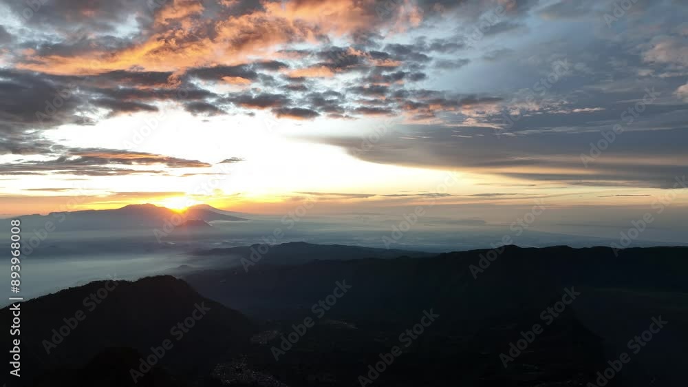 Beautiful sunrise over the mountains with orange clouds in mountainous landscape on East Java, Indonesia Beautiful sunrise over the mountains with orange clouds in mountainous landscape on East Java, Indonesia