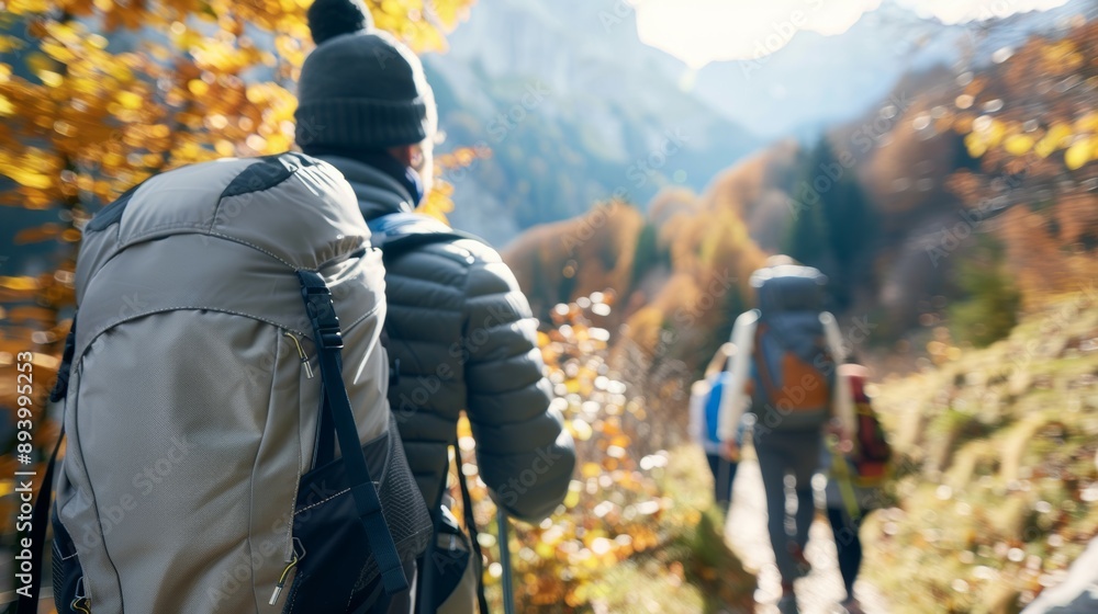 A man wearing a hat and a backpack is walking on a trail with two other people A man wearing a hat and a backpack is walking on a trail with two other people