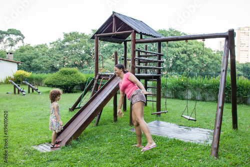 African American mother playing with Caucasian daughter on playground. photo