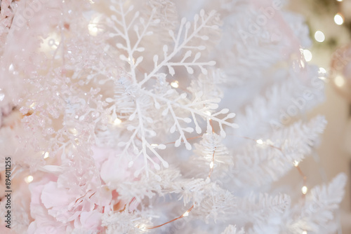 Christmas sparkling pastel background.Christmas white snowflakes on white snowy branches on a blurred beige background. Glowing garlands and Christmas decor.