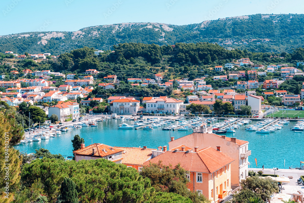 Panoramic view of Rab town with red tiled roofs and mountains on horizon. Rab island, Croatia Panoramic view of Rab town with red tiled roofs and mountains on horizon. Rab island, Croatia