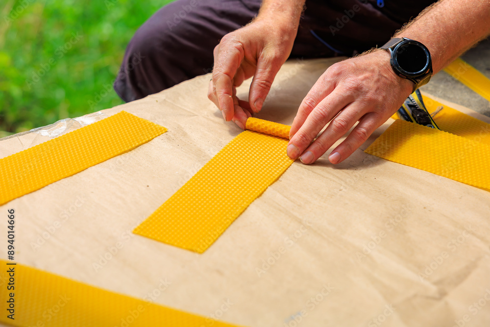 A man rolls decorative candle made of natural beeswax A man rolls decorative candle made of natural beeswax