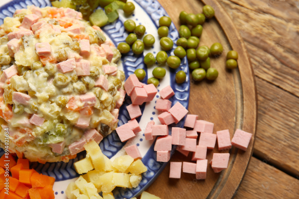Plate of tasty Olivier salad and ingredients on wooden background, closeup Plate of tasty Olivier salad and ingredients on wooden background, closeup