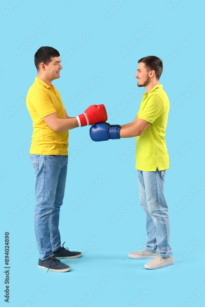 Handsome young brothers with boxing gloves on blue background Handsome young brothers with boxing gloves on blue background