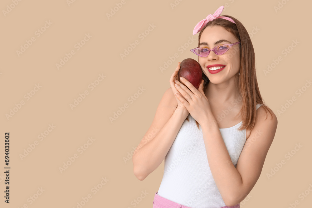 Happy young woman with sweet mango fruit on beige background Happy young woman with sweet mango fruit on beige background