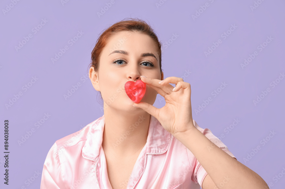 Beautiful young woman covering mouth with heart-shaped soap bars on lilac background Beautiful young woman covering mouth with heart-shaped soap bars on lilac background