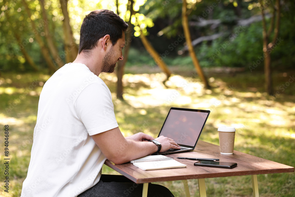 Freelancer working with laptop at table outdoors on sunny day. Remote job Freelancer working with laptop at table outdoors on sunny day. Remote job