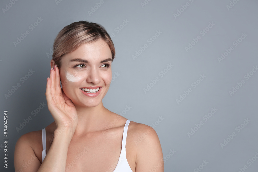 Beautiful woman with cream on her face against gray background, space for text Beautiful woman with cream on her face against gray background, space for text