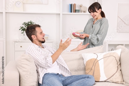 Happy young couple with pregnancy test on sofa at home