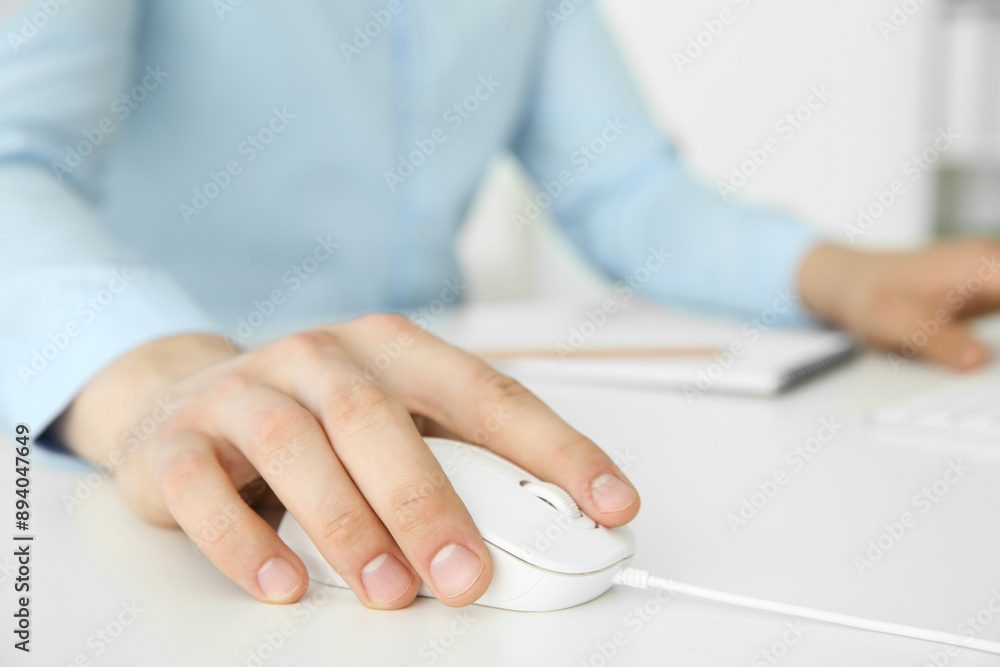 Man working with wired mouse at white table indoors, closeup Man working with wired mouse at white table indoors, closeup