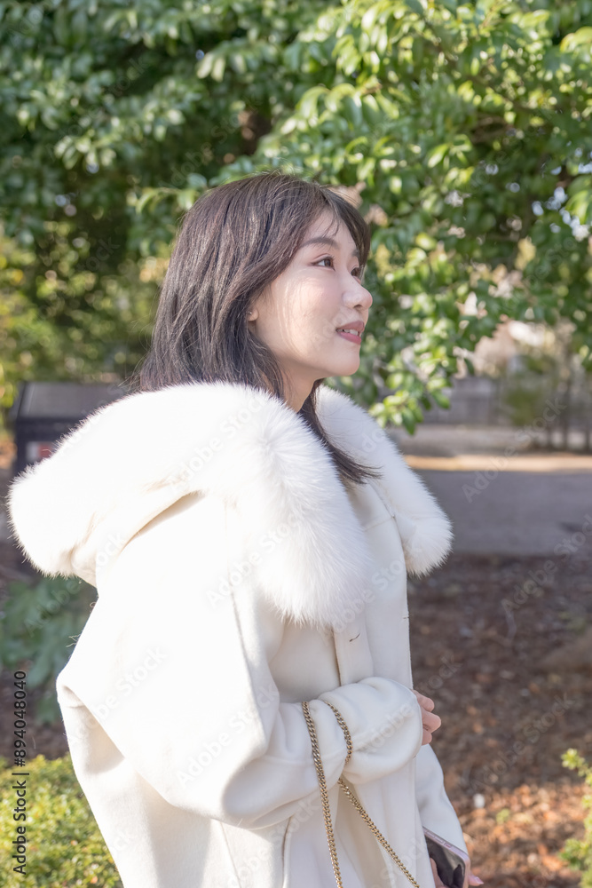 Twenty-something Chinese woman with black hair wearing a white coat with a fluffy fur hood and a white skirt walking on a public road in Minato, Tokyo, Japan. Twenty-something Chinese woman with black hair wearing a white coat with a fluffy fur hood and a white skirt walking on a public road in Minato, Tokyo, Japan.