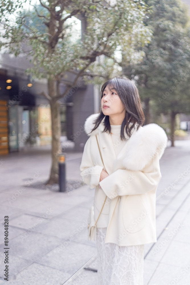 Twenty-something Chinese woman with black hair wearing a white coat with a fluffy fur hood and a white skirt walking on a public road in Minato, Tokyo, Japan. Twenty-something Chinese woman with black hair wearing a white coat with a fluffy fur hood and a white skirt walking on a public road in Minato, Tokyo, Japan.