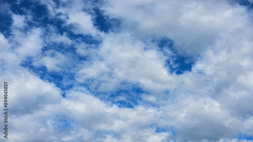 Fototapeta premium Background texture of white fluffy clouds in a dark blue sky in a 16_9 aspect ratio.