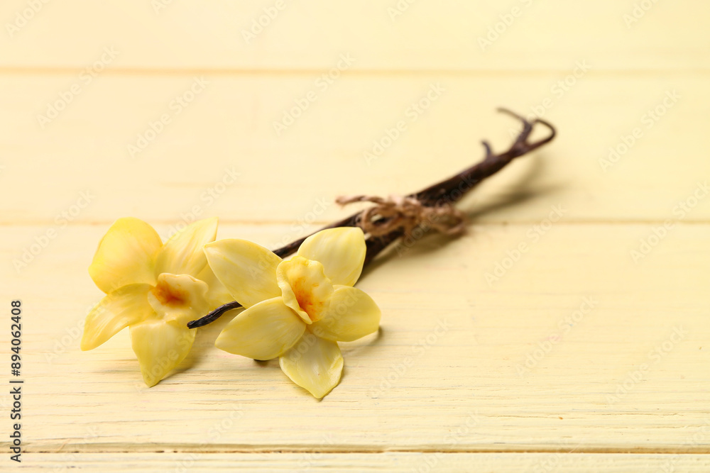 Beautiful vanilla flowers and sticks on yellow wooden background Beautiful vanilla flowers and sticks on yellow wooden background