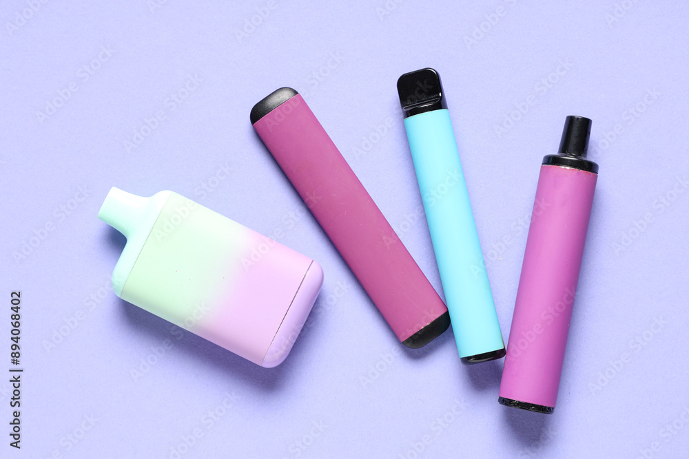 Different electronic cigarettes on lilac background Different electronic cigarettes on lilac background