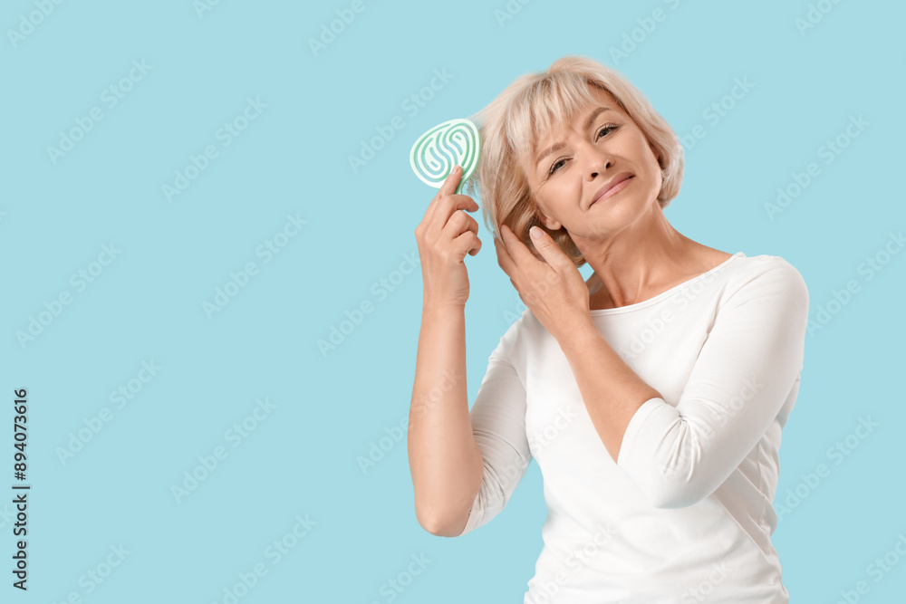 Beautiful mature happy woman with hairbrush on blue background Beautiful mature happy woman with hairbrush on blue background