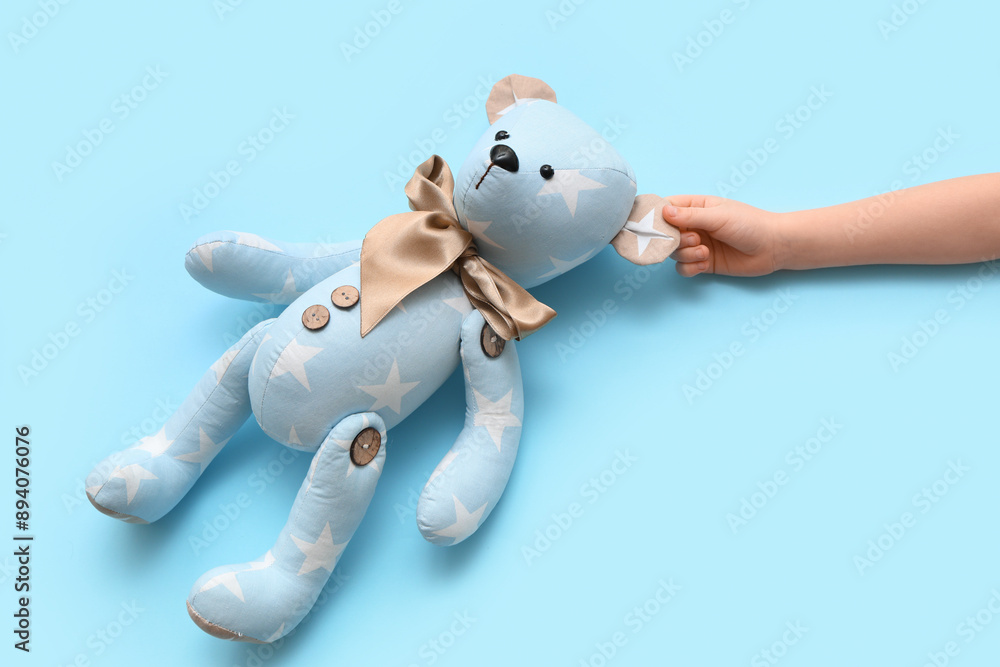 Obraz premium Child's hand with teddy bear on color background
